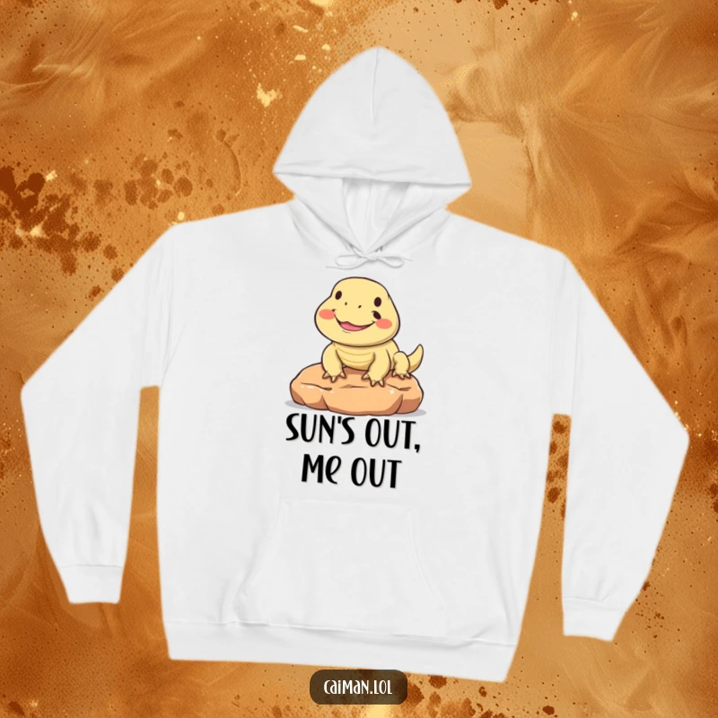 Funny hoodie showcasing a round, friendly reptile with a wide, joyful smile, basking happily on a warm stone, perfect for chilly days.
