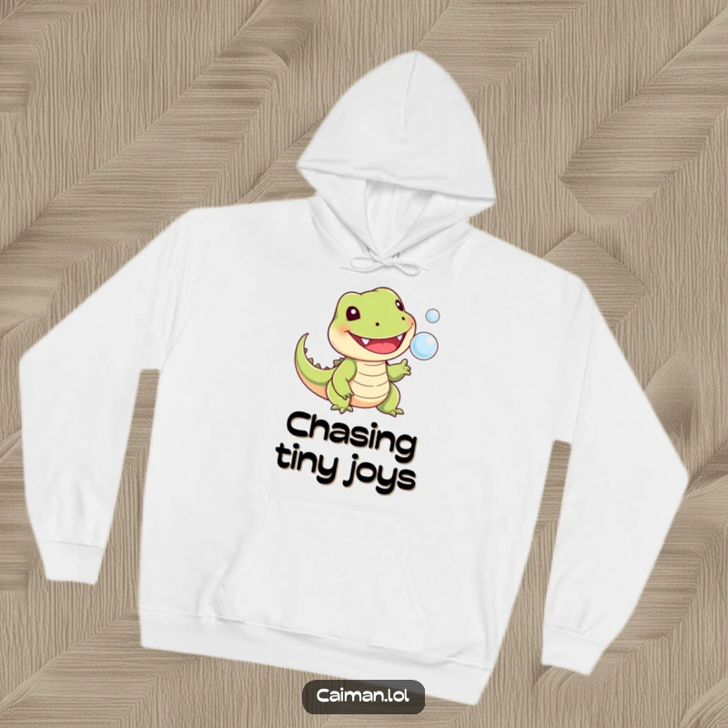 Funny hoodie illustrated with a cheerful, toothy reptile with a stubby tail, playfully snapping at a tiny floating bubble, perfect for cozy days.