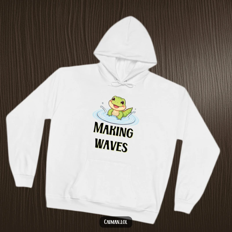 Funny Hoodie showing a small, cute reptile with a wide, happy grin splashing in a gentle, rippling puddle, perfect for cozy vibes.